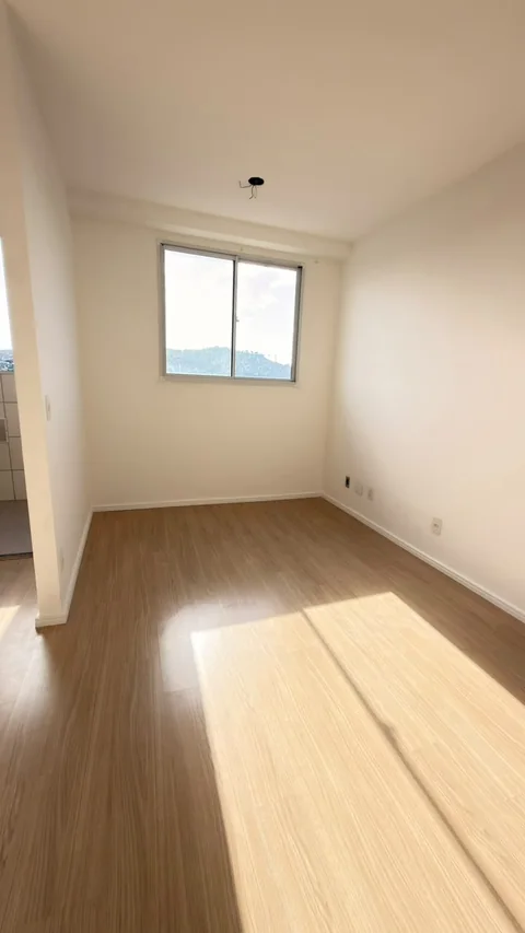 Sala iluminada com janela e piso amadeirado no apartamento visitado